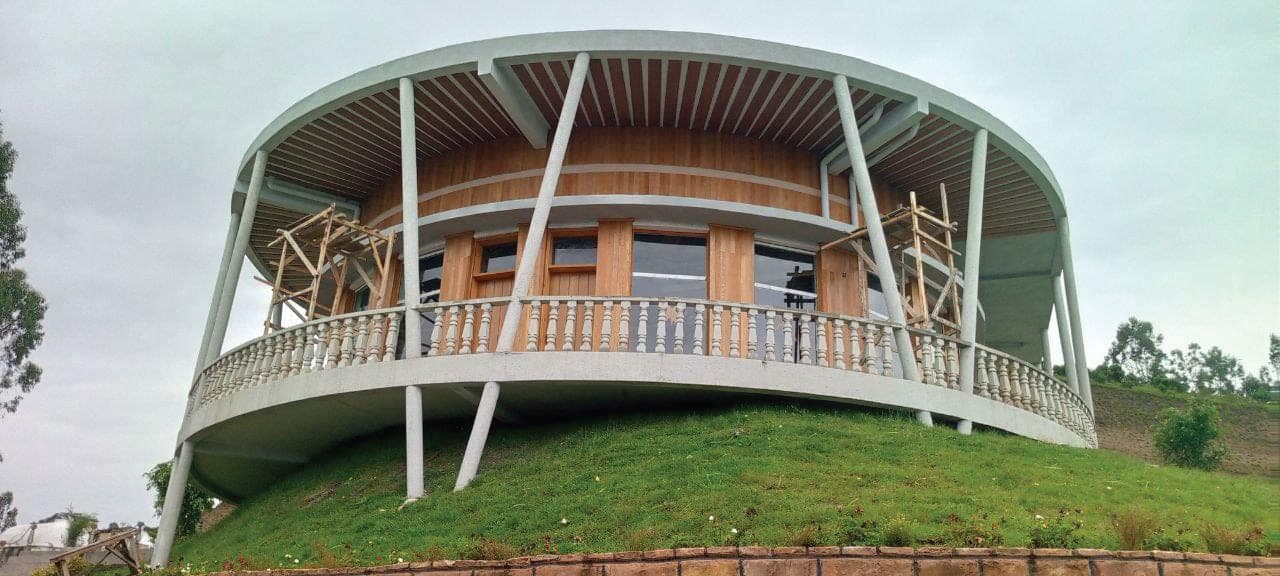 Curved timber-clad building with balustrade completed on a green hillside